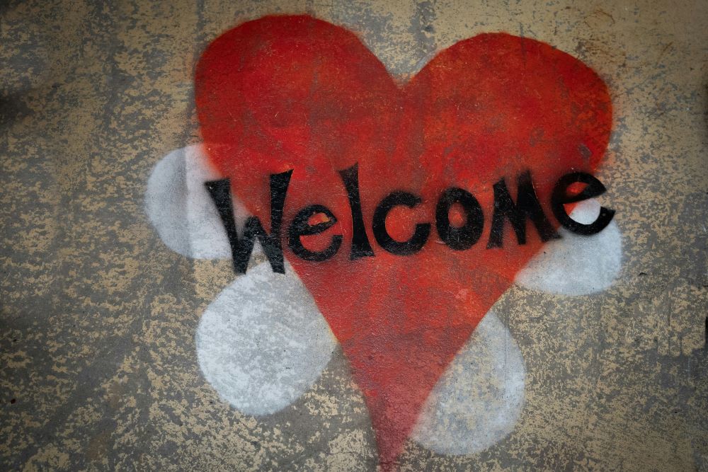 A welcome sign drawn in chalk, a heart sitting on a flower