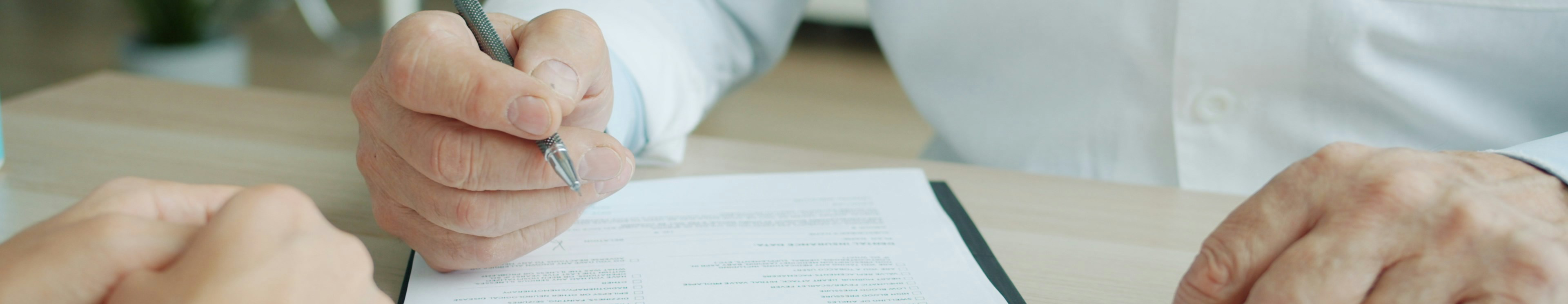 A doctor signing a paper on a clipboard
